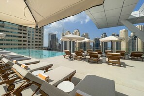 A rooftop pool area with lounge chairs and umbrellas, overlooking a cityscape with high-rise buildings. - 1 Bed City and Marina Views l Vida Residences (Dubai Marina)