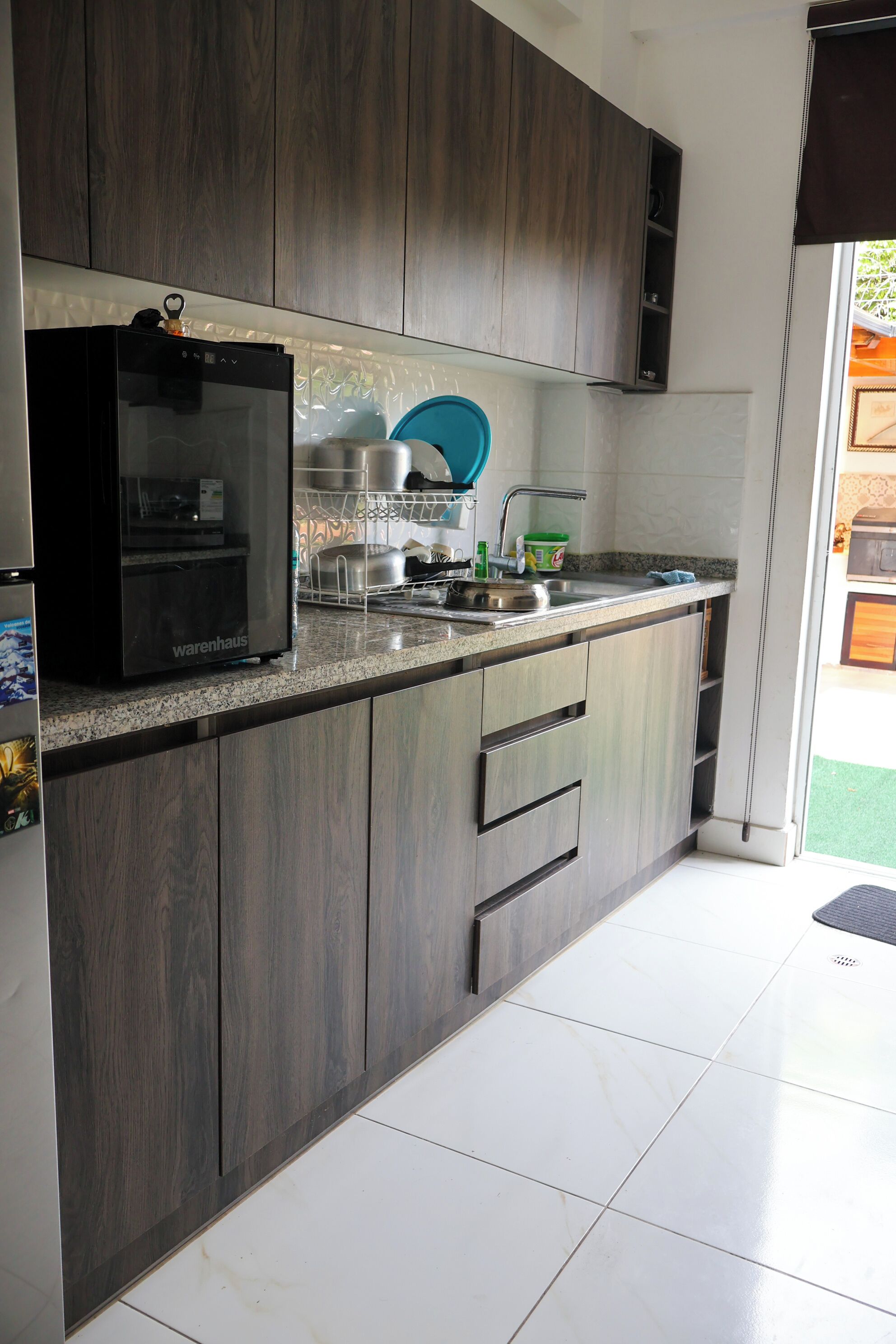 A modern kitchen with dark wood cabinets, a stainless steel refrigerator, and a granite countertop.