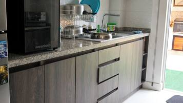 A modern kitchen with dark wood cabinets, a stainless steel refrigerator, and a granite countertop.