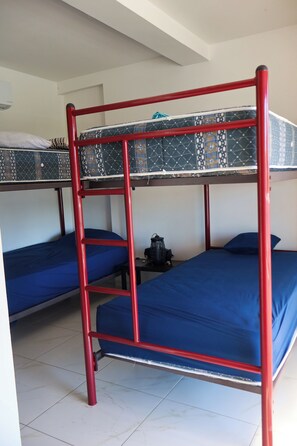 Un dormitorio con literas, una mesita pequeña y un calefactor.