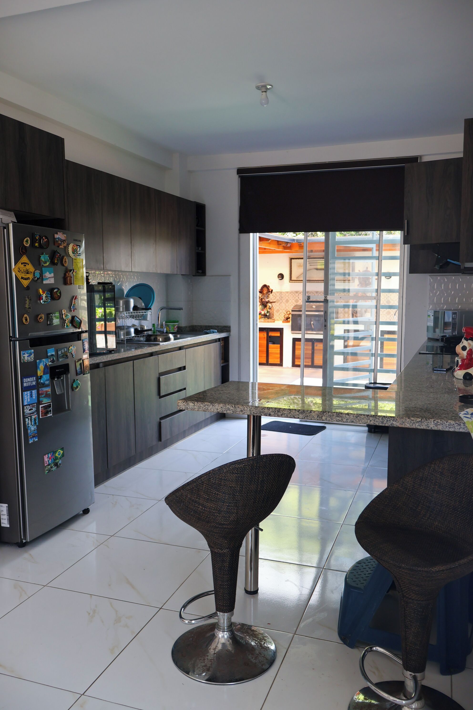 Eine moderne Küche mit Kühlschrank, Mikrowelle und Essbereich mit zwei Barhocker.