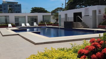 A swimming pool with lounge chairs and a small building with a door and steps.