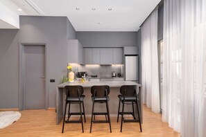 Eine moderne Küche mit grauen Schränken, einer zentralen Kochinsel mit Barhocker und einem Kühlschrank.