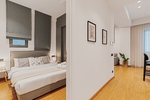 A modern hotel room with a large bed, a small bedside table, a window with blinds, and a view of the room. - Entire 2nd-Floor Home · 3 Bedrooms · Sleeps 7 · Central Athens, Private Terrace (Athina)