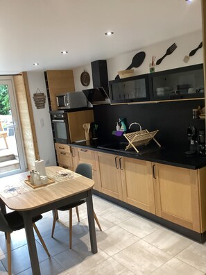 Cozinha moderna com armários de madeira, bancada preta e mesa de jantar com cadeiras.