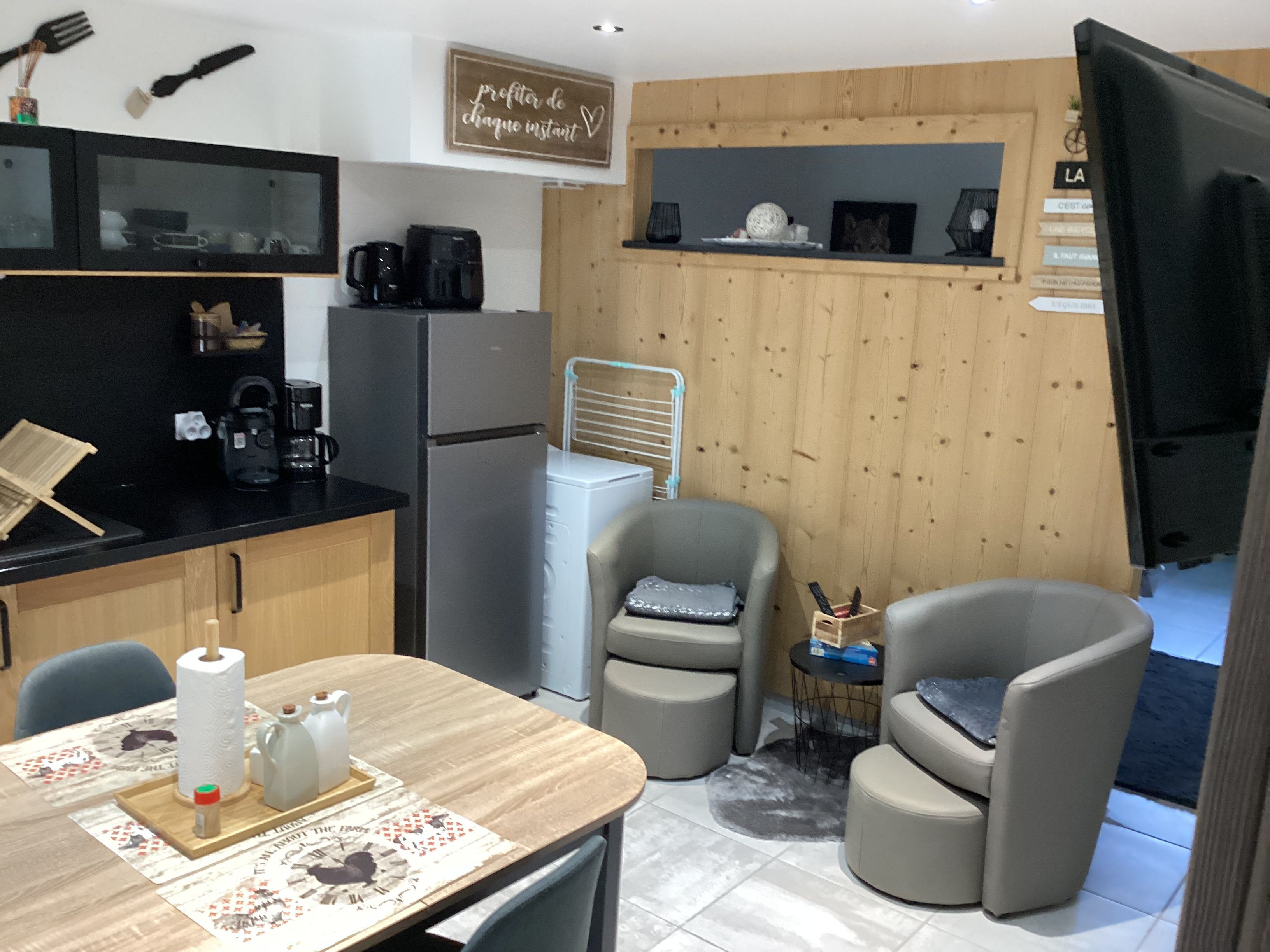 A compact kitchen with a refrigerator, coffee maker, and a small dining area with a table and two chairs.