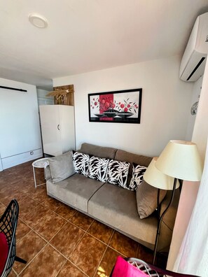 A living area with a sofa, a small side table, a lamp, and a painting on the wall. - Mirador of the Mediterranean, (Peñíscola)