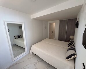 Une chambre à coucher avec un lit, une armoire, un miroir et une décoration en forme d’étoile de mer.