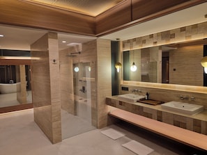 A modern bathroom with a glass-enclosed shower, a large mirror, and a wooden vanity with two sinks. - Uluviu Villa (Badung)
