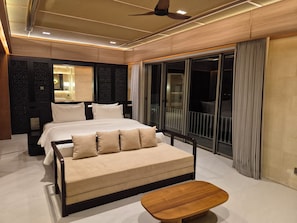 A modern bedroom with a bed, sofa, and a small wooden table. - Uluviu Villa (Badung)