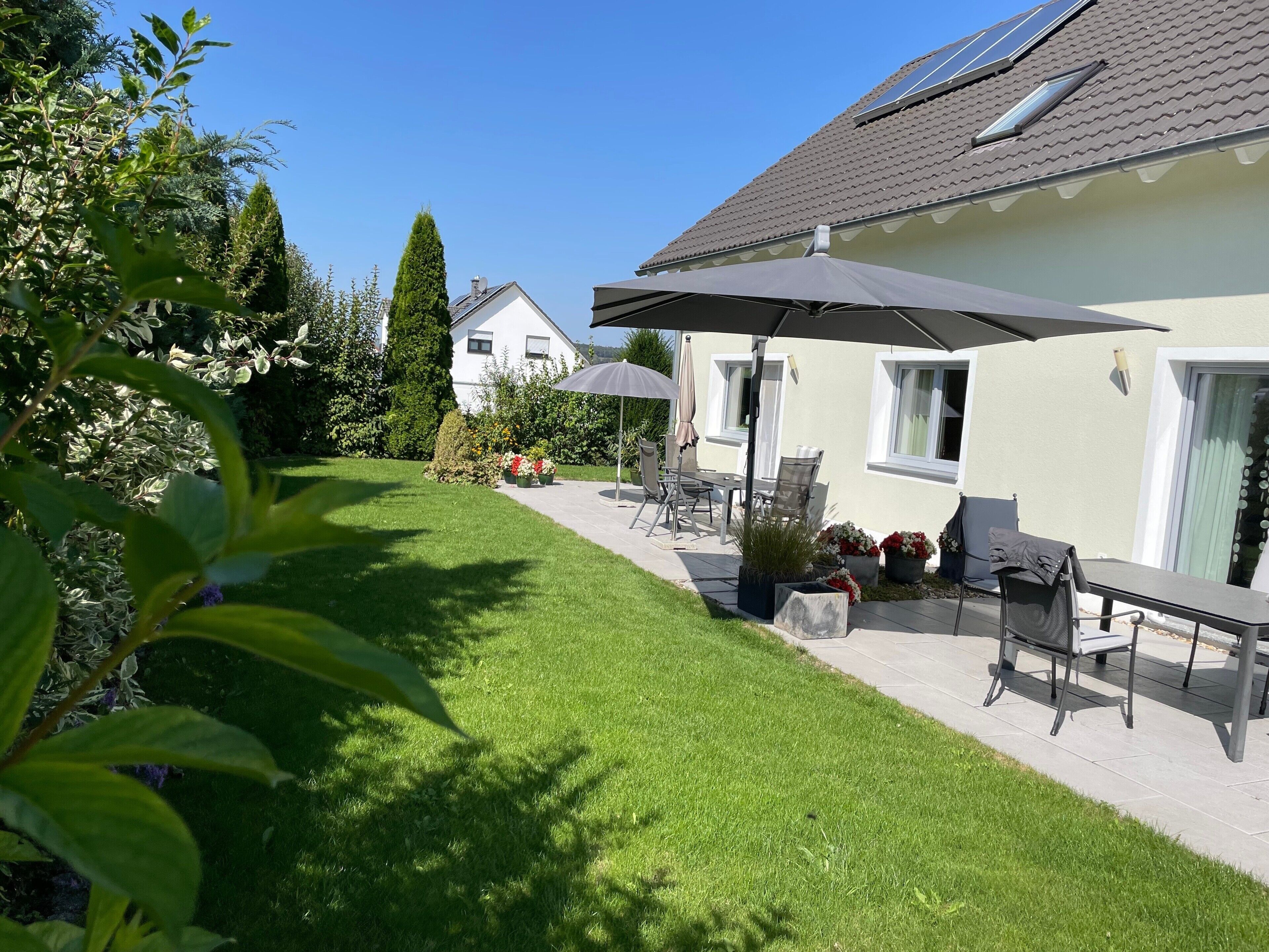 Une maison dotée d’un patio, de mobilier d’extérieur et d’une pelouse bien entretenue.
