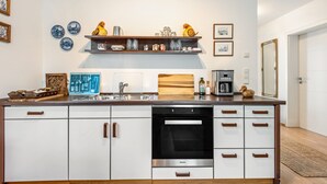 A modern kitchen with white cabinetry, a built-in oven, and a coffee machine.