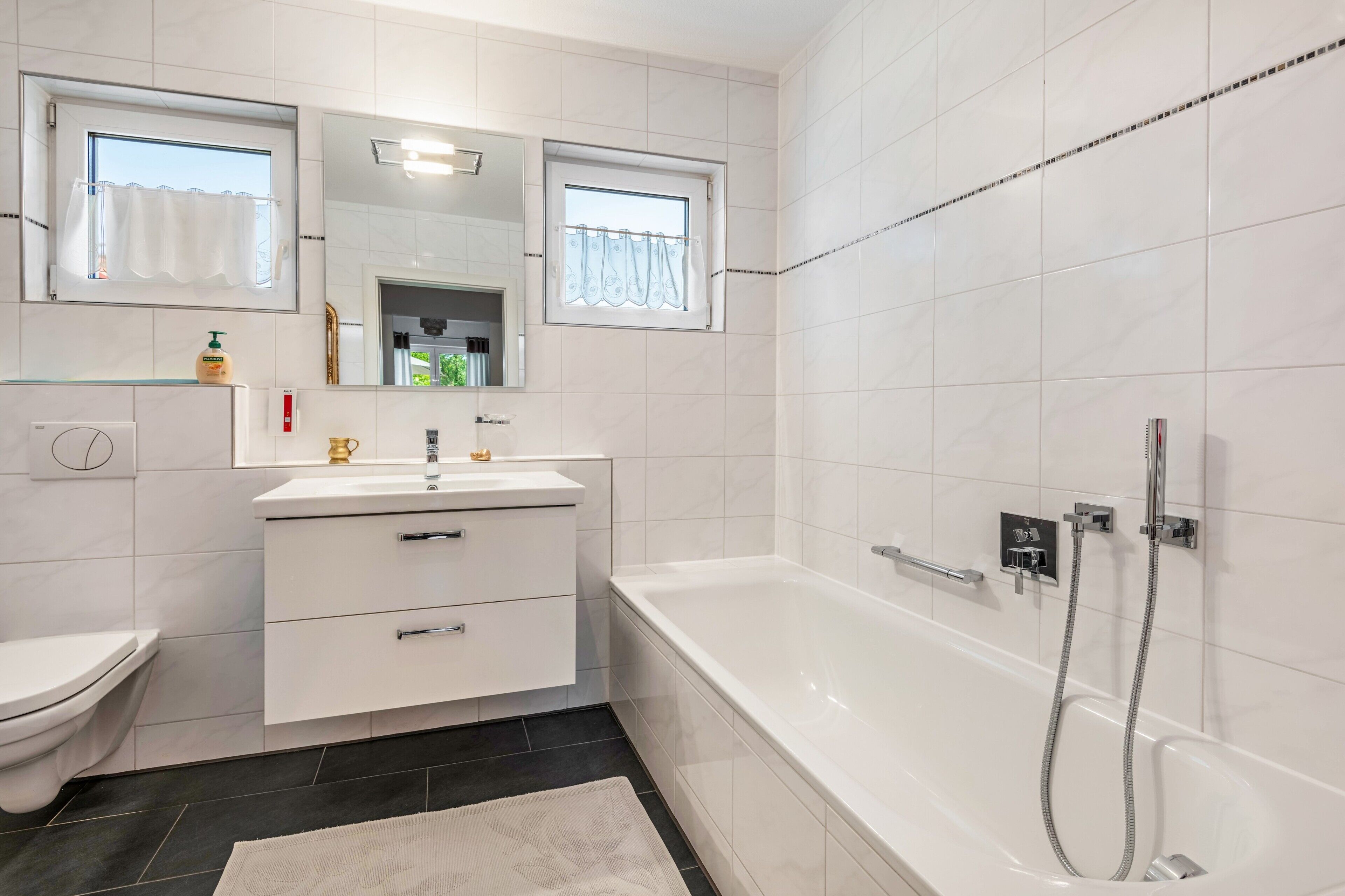 A modern bathroom with a bathtub, toilet, and vanity.