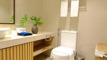 A bathroom with a toilet, bidet, sink, and a mirror.