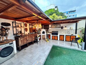 A kitchen with a built-in grill, a washing machine, and a rustic wooden cabinet.