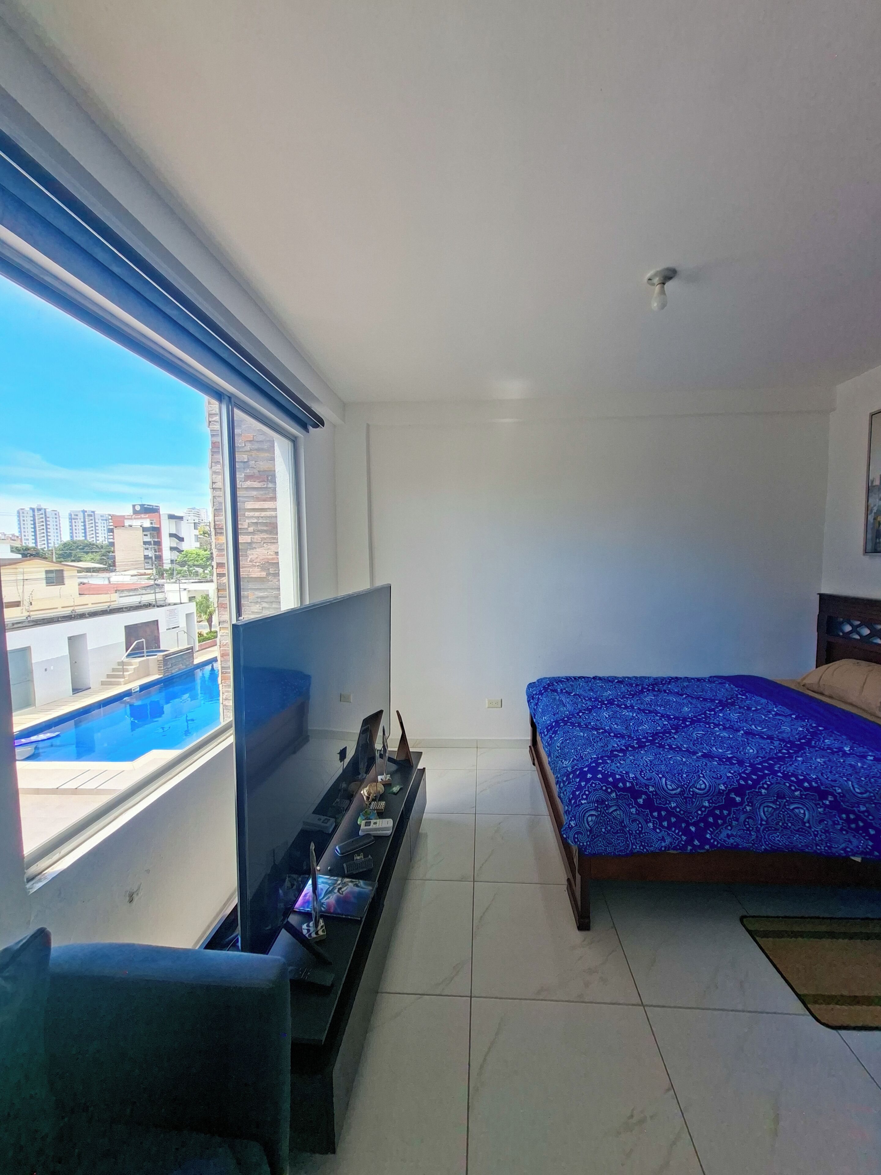 Une chambre avec un lit, une télévision et une vue sur une piscine.