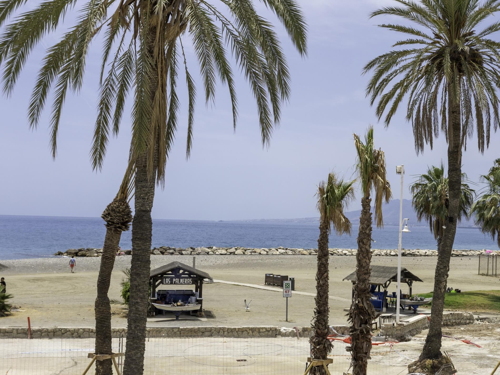A beach scene with palm trees, a small boat, and a sign reading 'Las Palmas'.