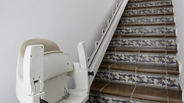 Eine Treppe mit aufwendigen Fliesen und ein weißer Stuhl mit beigem Kissen.