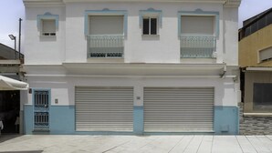 Ein zweistöckiges Gebäude mit einer Garagentür, einem Balkon mit Metallgeländern und einem kleinen Fenster.