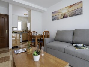 A modern living room with a grey sofa, wooden dining table, and a kitchen in the background. - Sunstay Pedregal A Flat I Málaga (Málaga)