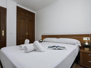 Une chambre d’hôtel avec un lit, une table de chevet, une lampe et une armoire.