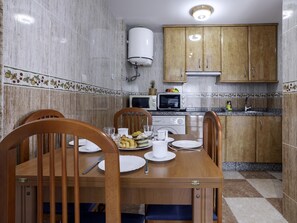Une cuisine compacte comprenant une table à manger pour deux personnes, un four à micro-ondes et un évier.