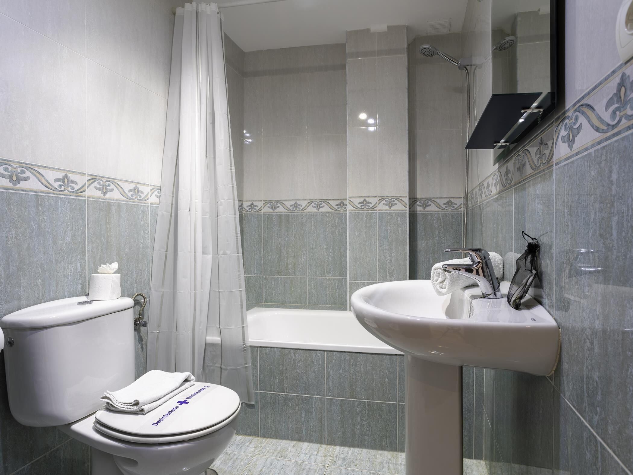 A bathroom with a toilet, shower, and sink.