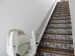 Eine Treppe mit aufwendigen Fliesen und ein weißer Stuhl mit beigem Kissen.