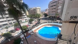 A rooftop pool with a clear blue pool, surrounded by lounge chairs and a palm tree. - Sunstay Lovely Loft Fuengirola (Fuengirola)
