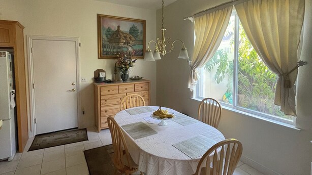 A dining room with a round table, chairs, a chandelier, a painting on the wall, and a window with curtains. - Perfect for a traveling professional! (Clovis)
