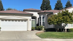 A residential property with a garage, a driveway, and a well-maintained lawn. - Perfect for a traveling professional! (Clovis)