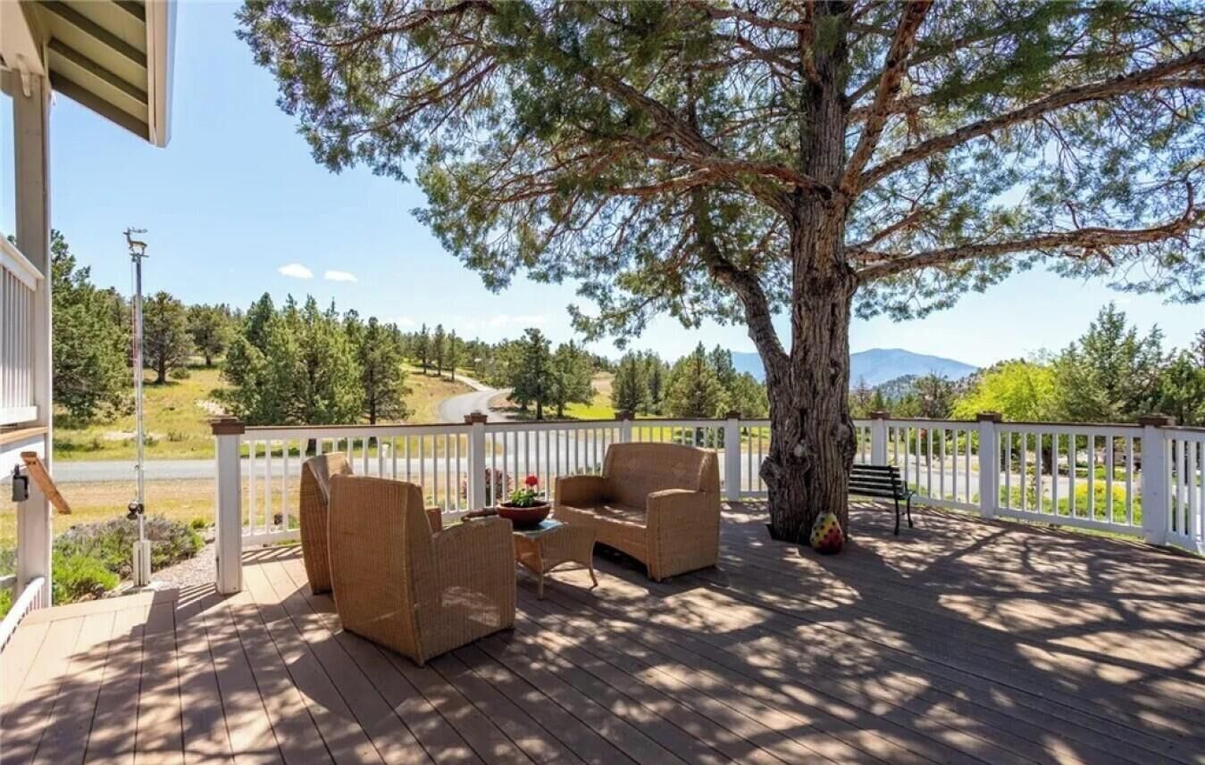 A wooden deck with wicker furniture and a view of a mountainous landscape.
