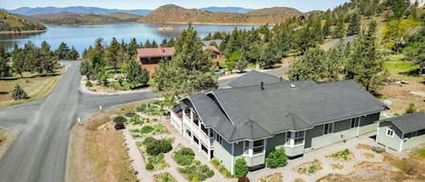 Una casa de dos pisos con un amplio jardín delantero, un camino de entrada y un lago al fondo.