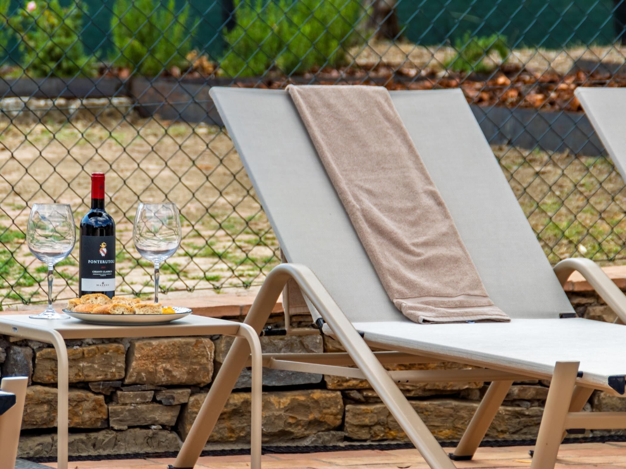 Un área de descanso con dos sillones reclinables, una mesa con una botella de vino, una copa y un plato de comida.
