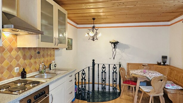 Una cucina con forno, pensili e zona pranzo con tavolo e sedie.