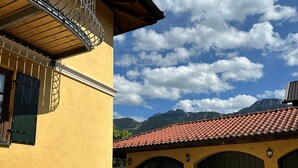 Un edificio giallo con tetto in tegole rosse, una scalinata e vista sulle montagne.