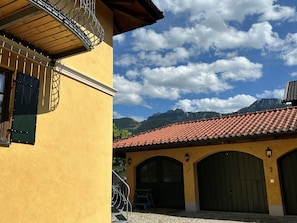 Ein gelbes Gebäude mit rotem Ziegeldach, einer Treppe und Blick auf Berge.