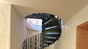 Eine Wendeltreppe mit aufwendiger Metallgeländerung und einem Holzstuhl unten.