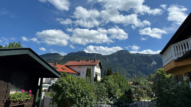 Ein Wohngebiet mit Häusern, Bergen im Hintergrund und blauem Himmel.