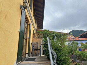 Entrada de um edifício com porta de madeira, uma cadeira e um portão de metal.
