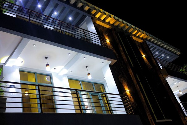 Un edificio de varios pisos con balcones, ventanas amplias e iluminación exterior.