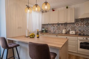 A kitchen with a wooden island, bar stools, hanging pendant lights, and a tiled backsplash. - Holiday Home in the Crikvenica Hinterland – Pool, Sauna & Complete Privacy (Tribalj)