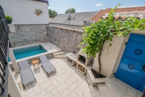 A pool area with lounge chairs, a barbecue grill, and a blue door. - Holiday Home in the Crikvenica Hinterland – Pool, Sauna & Complete Privacy (Tribalj)