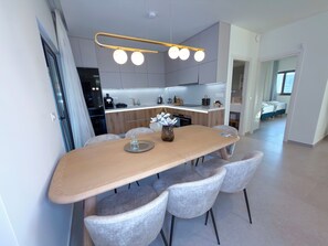 A modern kitchen with a central island, grey cabinets, and a pendant light fixture. - Cozy Villa Kissamos (Kissamos)