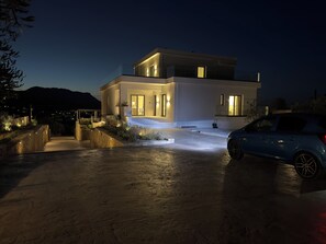Ein modernes, zweistöckiges Haus mit Auffahrt, einem geparkten Auto davor und einem Berg im Hintergrund.