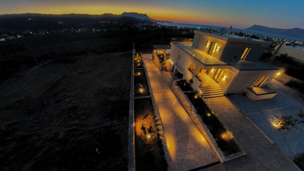 Une maison moderne dotée d’un balcon, d’une piscine et offrant une vue sur la mer et les montagnes.