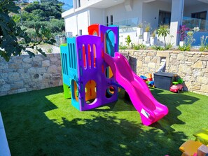 Ein Kinderspielbereich mit Rutsche und bunten Spielgeräten.