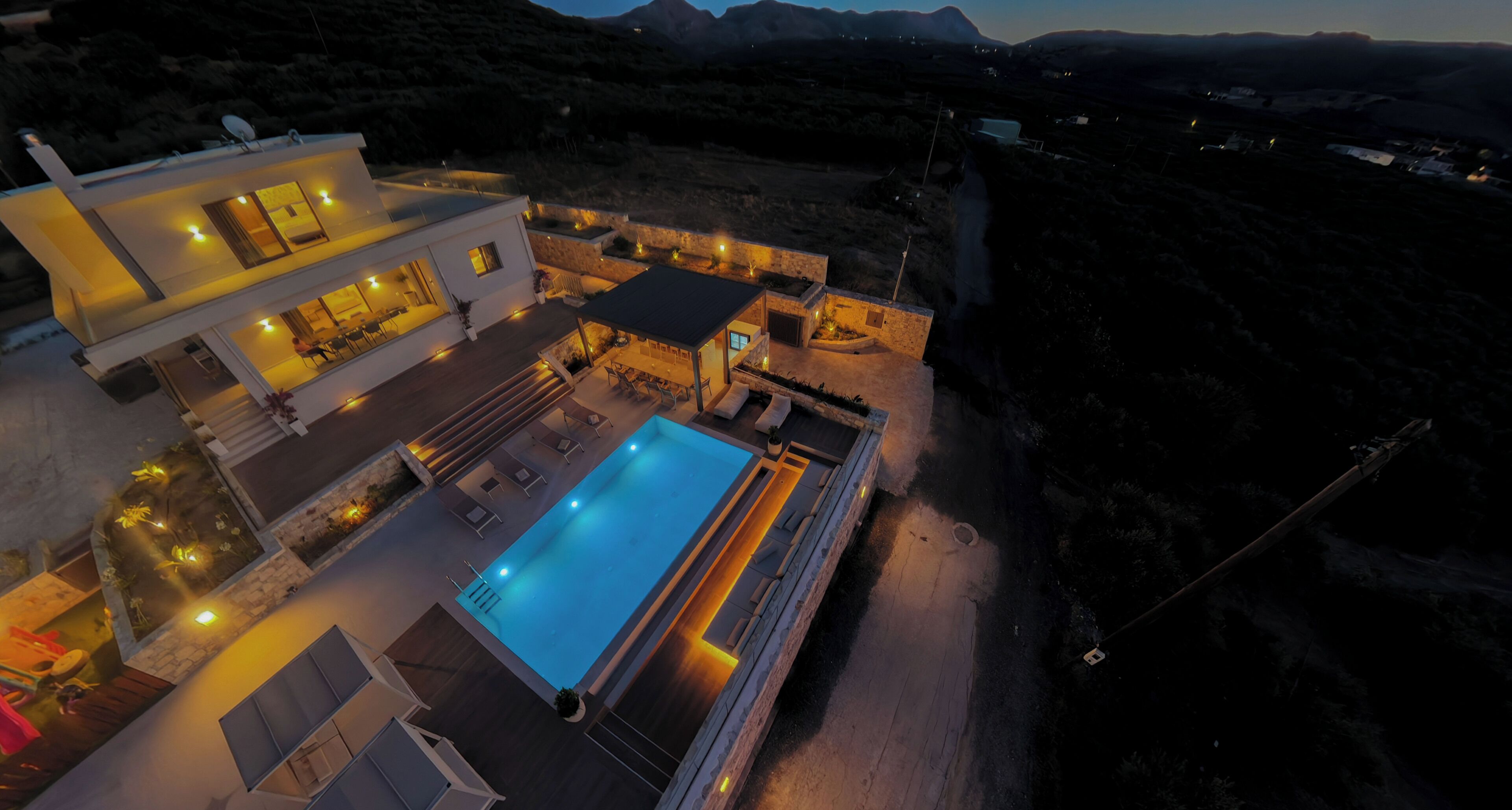 Une maison moderne à deux étages, dotée d’une piscine, d’un espace extérieur aménagé et offrant une vue sur le paysage environnant.