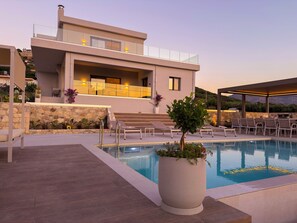 Ein moderner Poolbereich mit Liegestühlen, einem Schwimmbecken und einem Gebäude mit Balkon.