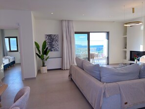 A modern living room with a sofa, a dining area, and a balcony with a view. - Cozy Villa Kissamos (Kissamos)